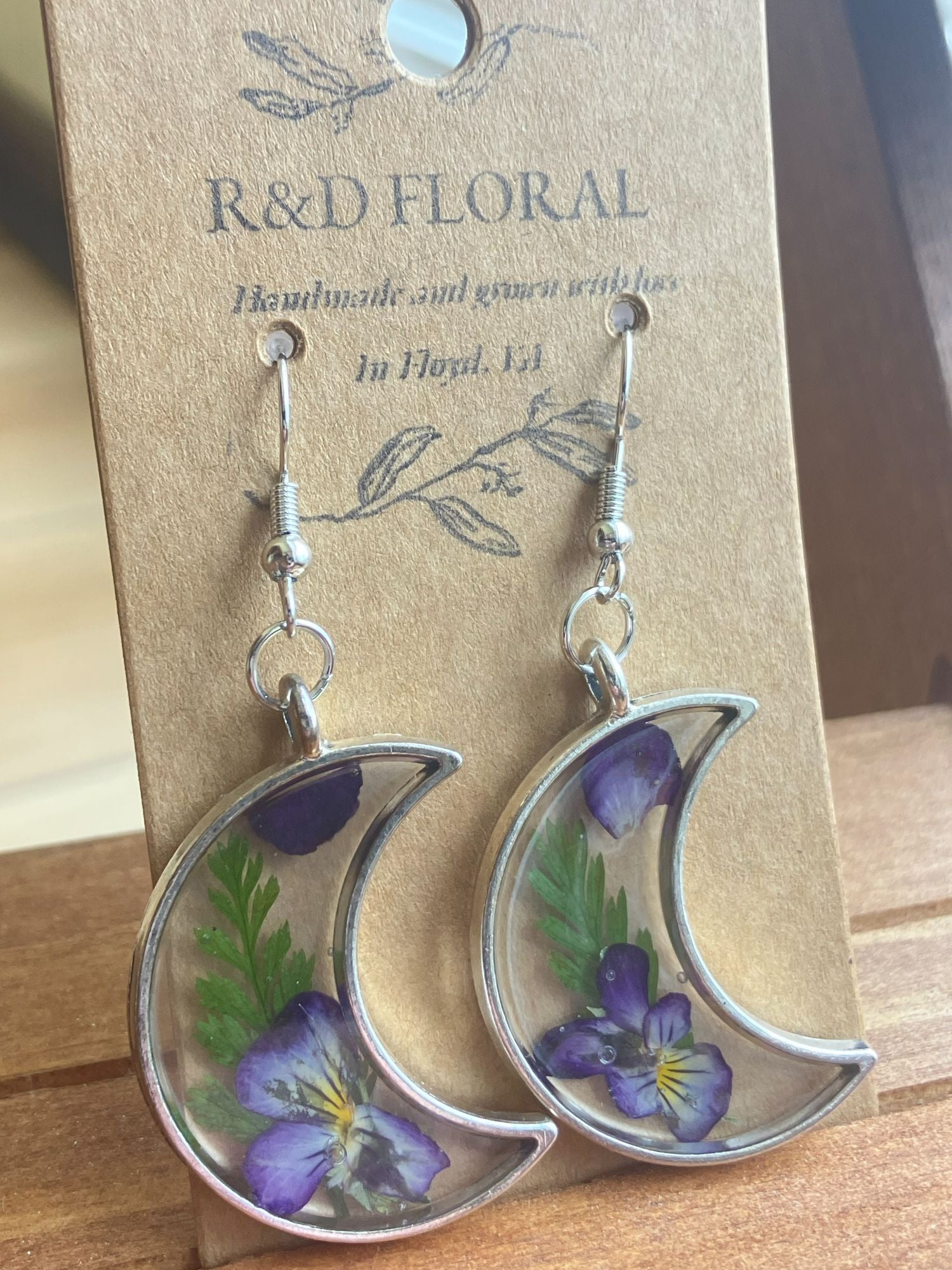 Silver moon-shaped earrings encasing real Violas and fern leaves in resin, handmade by R & D Floral.